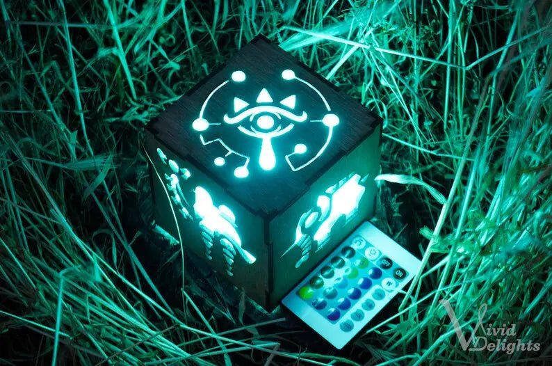 Illuminated Zelda Breath of the Wild inspired lantern with intricate designs, featuring remote control, nestled in grass.