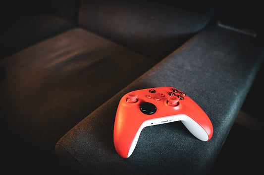 Red video game controller rests on a dark couch