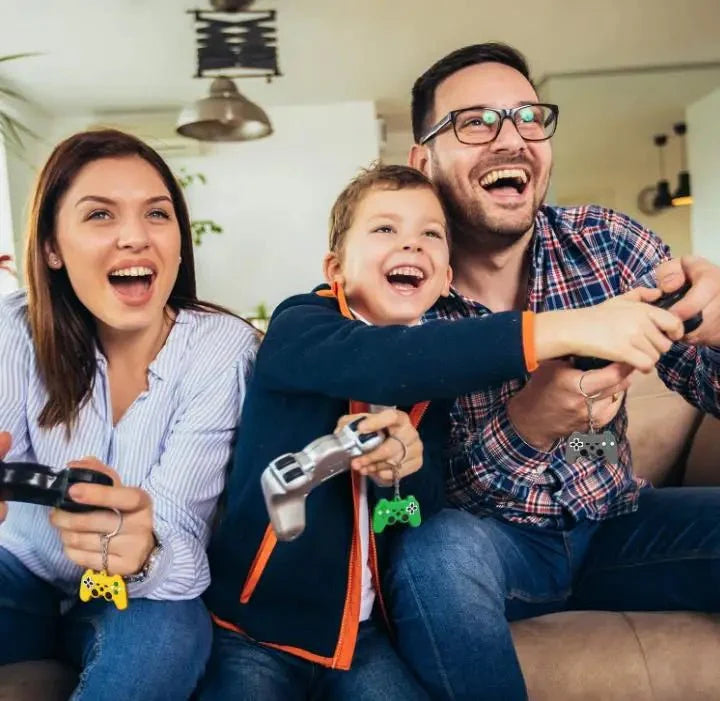 Family laughing while playing video games with Gapo goods game controller keychains