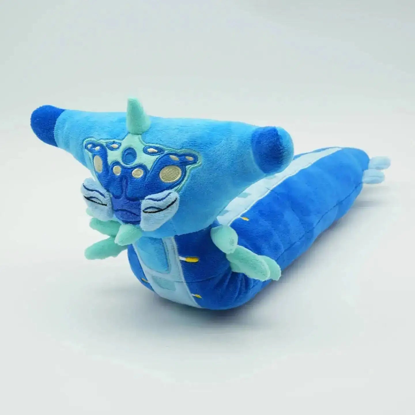 Blue plush toy with a cartoon face on a white background