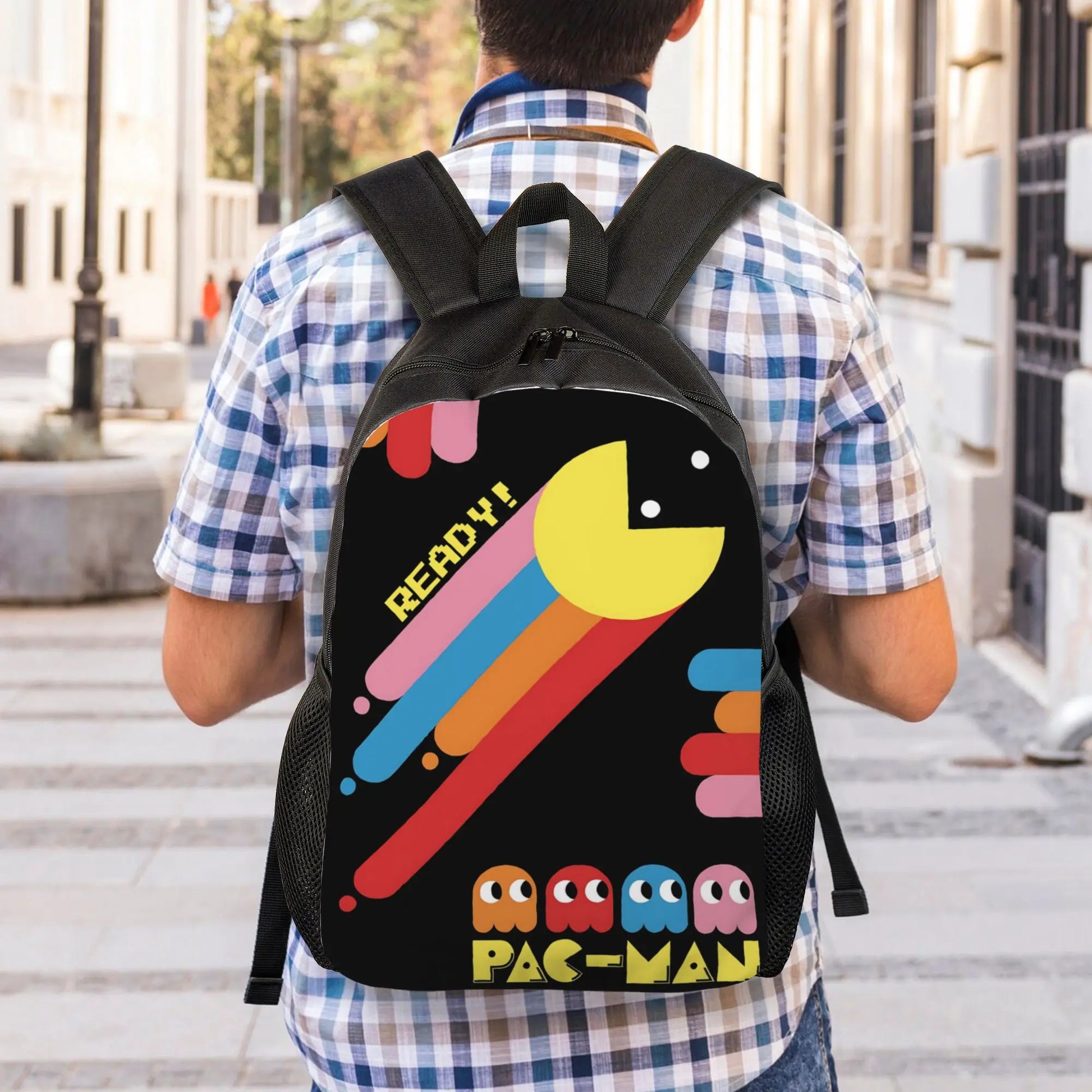Person wearing a black backpack with Pac-Man design outdoors.