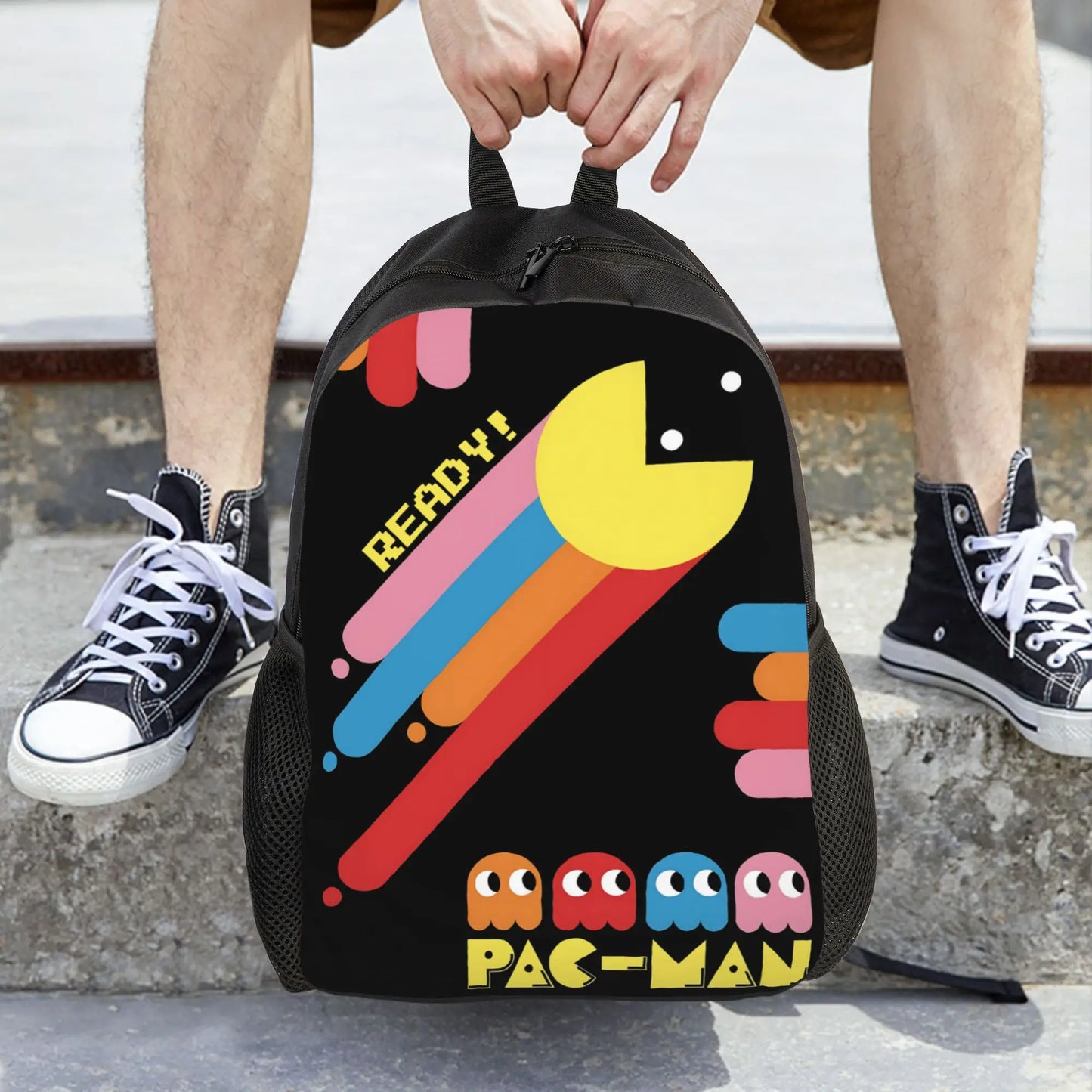 Pac-Man themed backpack held by a person wearing black sneakers.