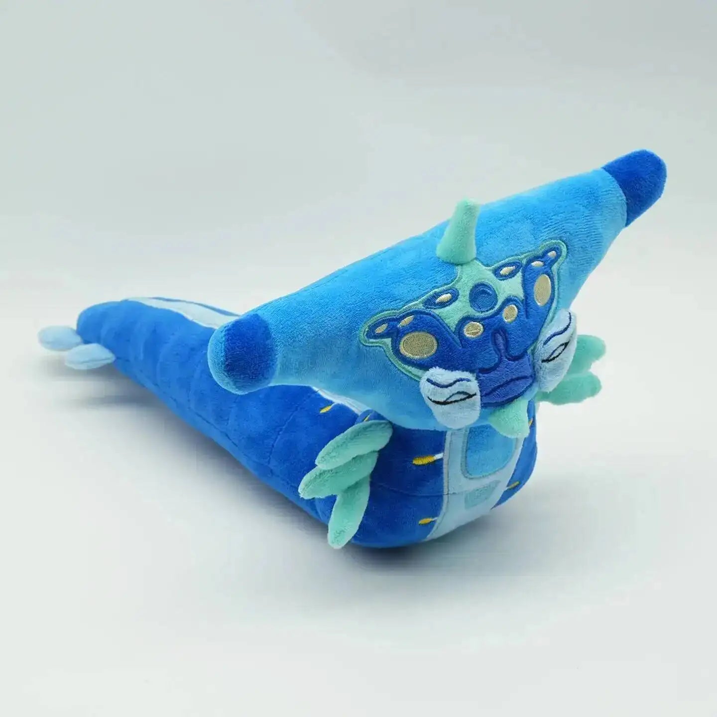 Blue plush toy with a dragon design on a white background