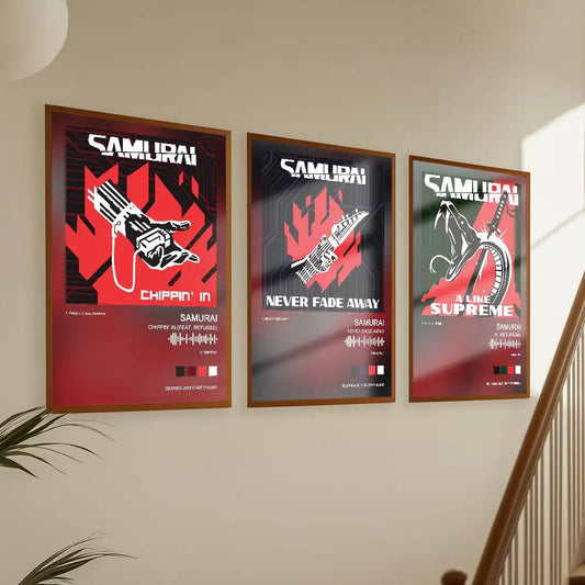 Three framed music posters for the band Samurai Wall, featuring their albums 'Chippin' N', 'Never Fade Away', and 'All Supreme', displayed on a beige wall next to a staircase.